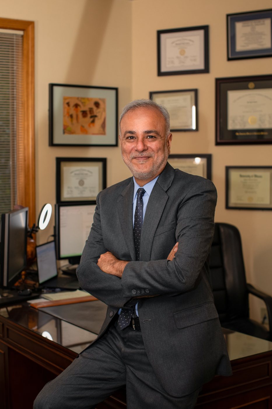 Dr. Saud Anwar seated in his office beneath framed diplomas