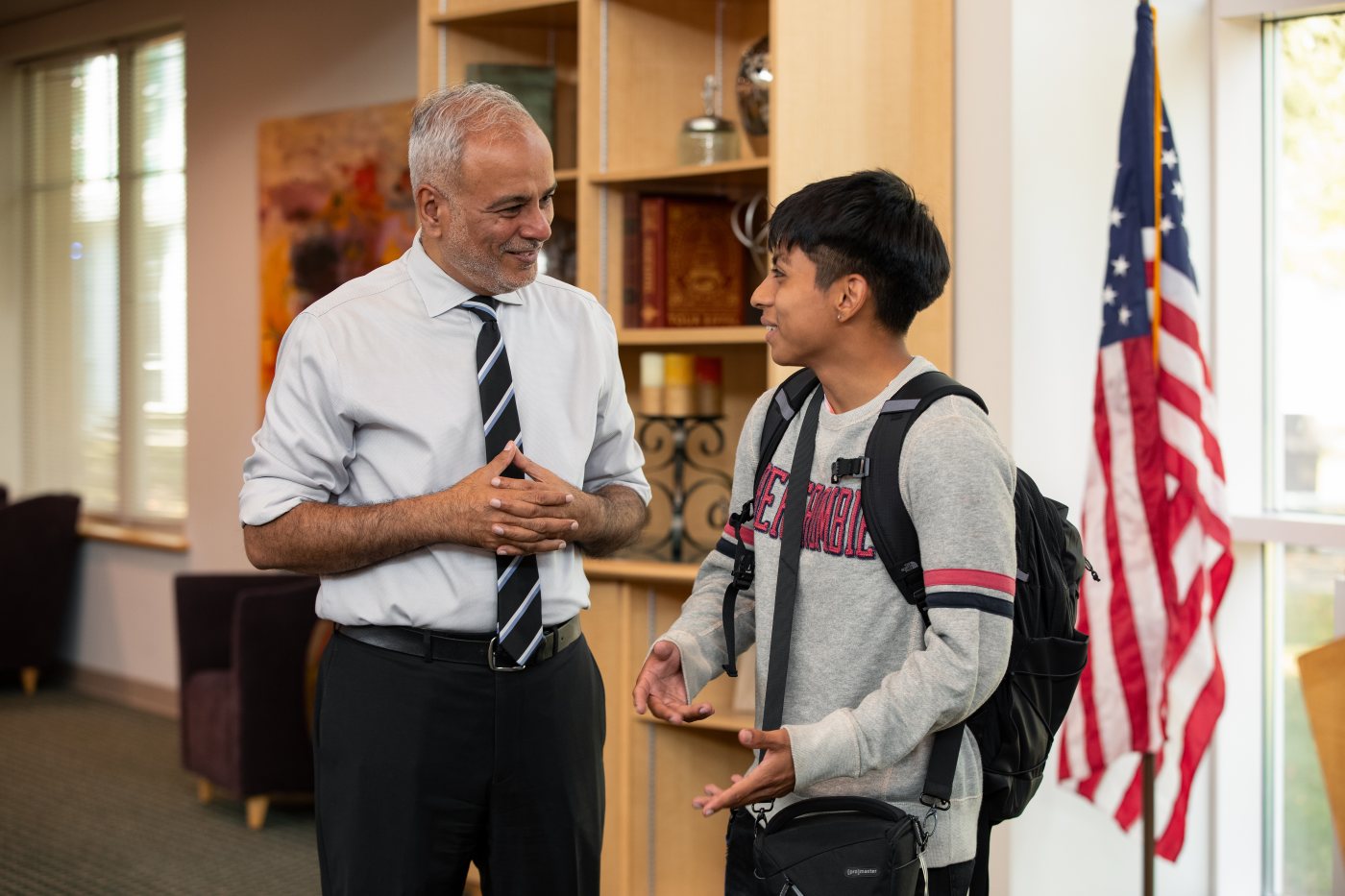 Dr. Saud Anwar talking with a student in a library