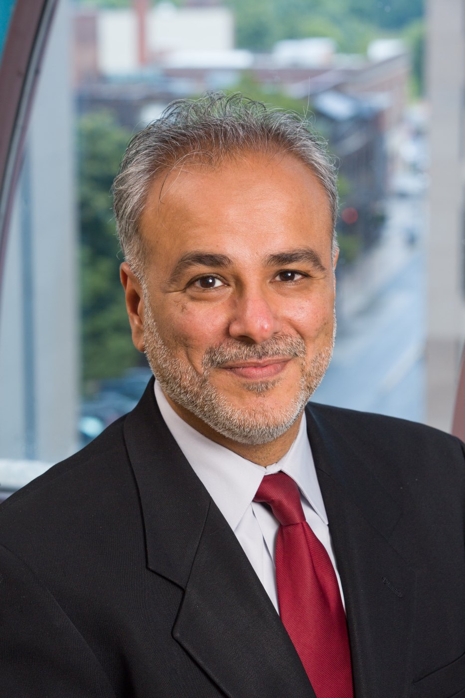 Studio headshot of Dr. Saud Anwar in a dark suit and red tie